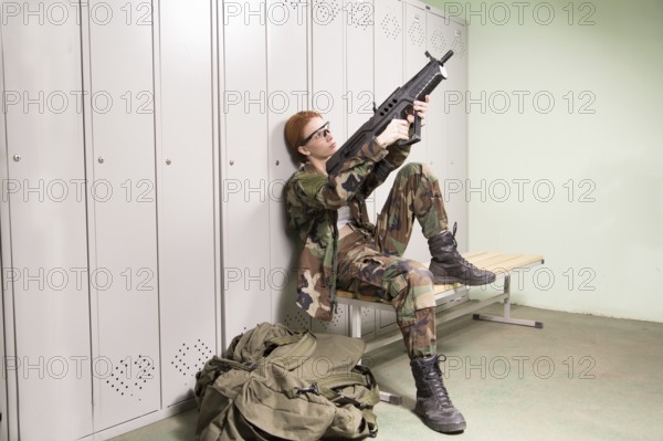 A shoot of young caucasian beautiful redhead woman sitting on the bench at locker room. ?hecking weapon