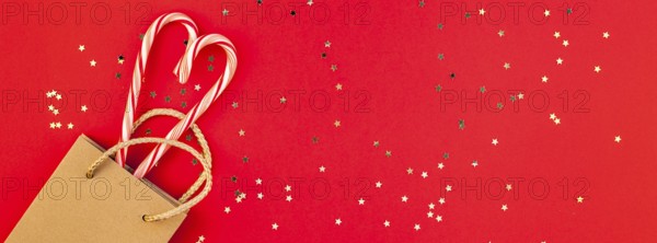 New Year or Christmas decoration flat lay top view Xmas holiday celebration shopping concept decor sweets golden stars glitter on red paper background. Template frame long wide banner
