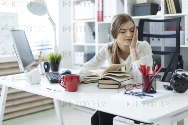 Beautiful young girl with blond hair. A girl in a white blouse and black pants is working in the office. photo with depth of field