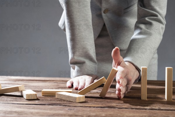 Business woman hand block domino effect. Business risk management and stabilisation situation. Life insurance company presentation with wooden blocks on table. Protection from economic crisis