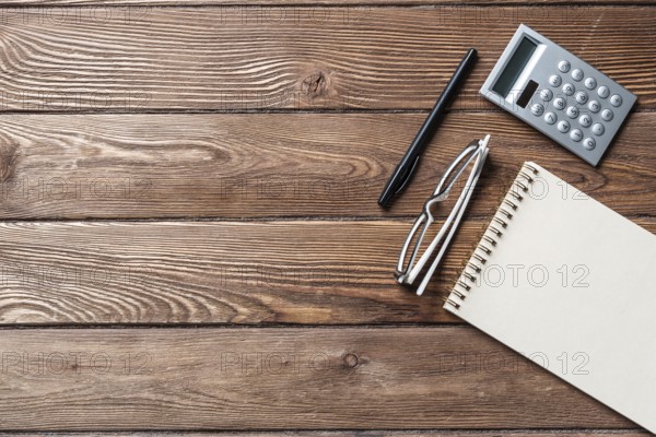 Still life of accountant vintage workspace with office accessories. Flat lay old hardwood desk with notepad, pen and calculator. Business analysis and consulting. Finance and investment concept