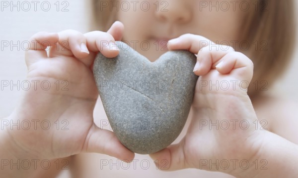 Child's hands hold heart from a stone