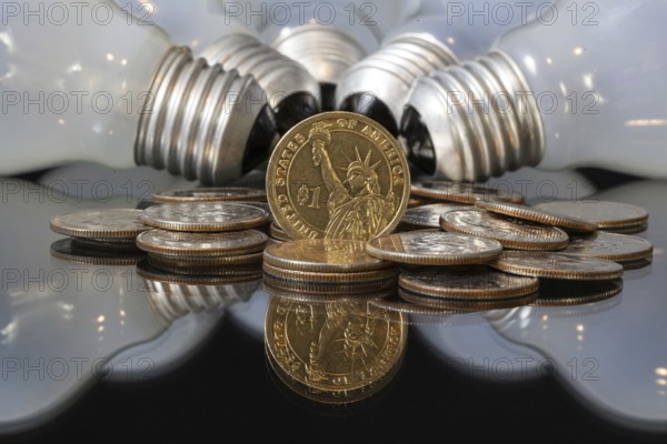 Wasteful bulbs and U.S. dollar coins on a black table