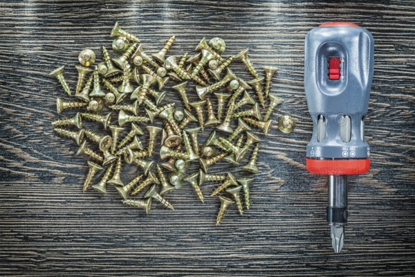 Screwdriver tapping screws on wooden board
