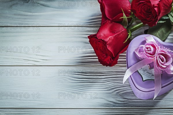 Metal heart-shaped gift box red roses on wooden board holidays concept