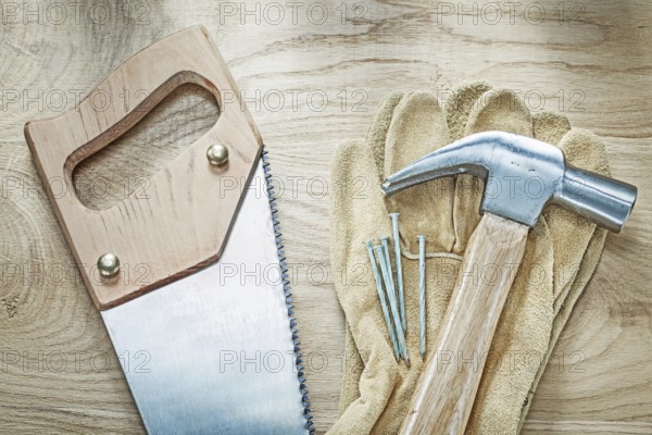 Claw hammer leather protective gloves handsaw nails on wooden board construction concept