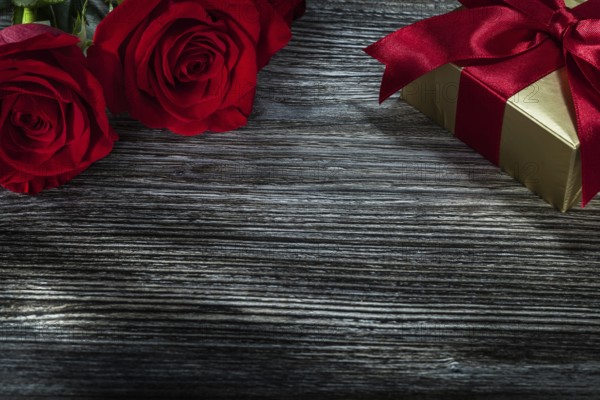Golden gift box red roses on wooden board