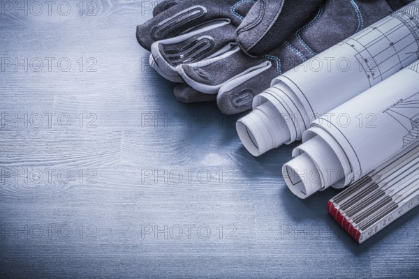 Rolled blueprints wooden meter and protective working gloves