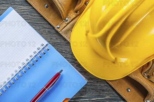 Notebook pen tool belt building helmet on wooden board
