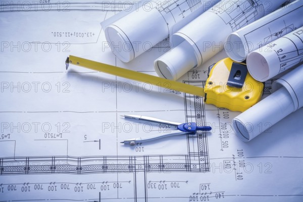 Rolled blueprints compass and yellow tapeline