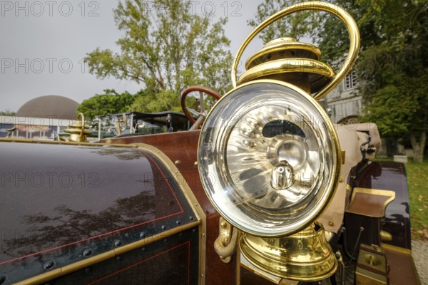 Lisbon, Portugal - Oct 15, 2023: Detail of 1904 Mercedes Simplex - external headlight in brass housing with reflective interior and glass lens. Round shape of antique car lantern-like headlight with incandescent bulb system
