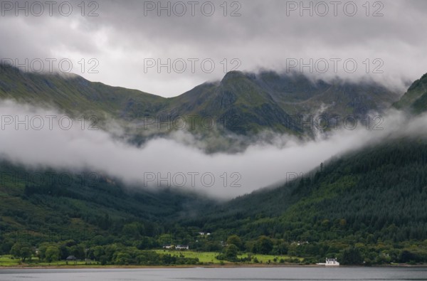 Idyllic mountain landscape with morning early fog covering the peaks at Fort Williams, Glencoe area in the Highlands of Scotland, United Kingdom, Europe