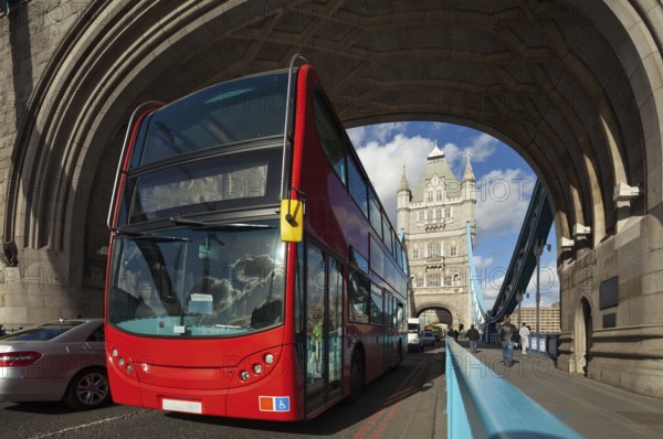 The famous Tower Bridge in London, UK. Double-decker bus passes under the arch of the tower. Sunny day. Photograph taken with the tilt-shift lens, vertical lines of architecture preserved