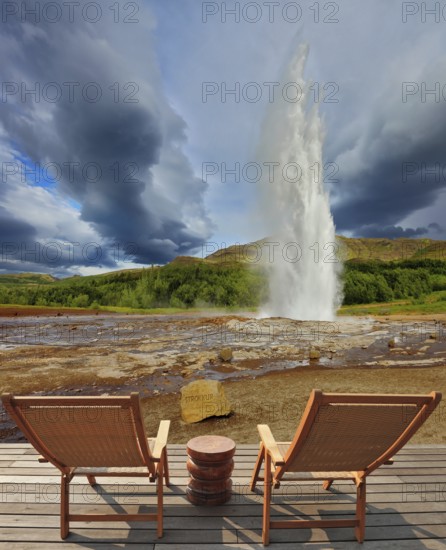 Pillar of hot water and steam from forcing its way out of the ground. Geyser Strokkur in Iceland. Two lounge chairs and small table on wooden platform for easy observation
