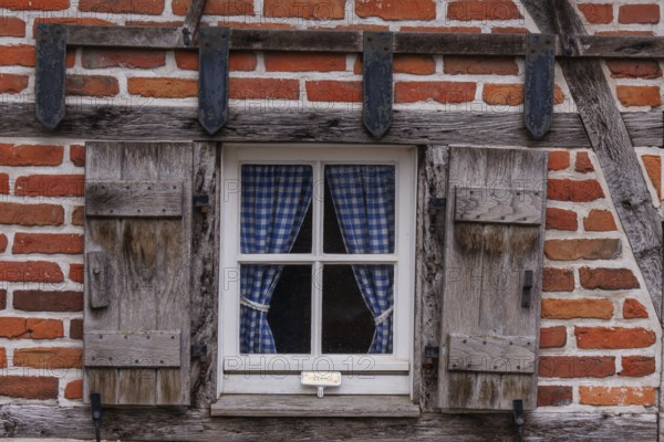 Rustic window with wooden frame and blue chequered curtains in a half-timbered house, weseke, münsterland, germany