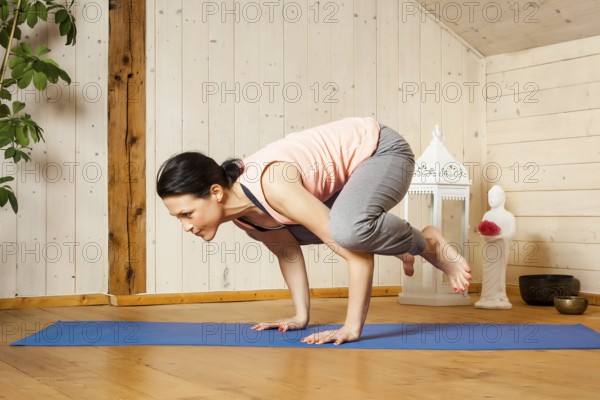An image of a pretty woman doing yoga at home - crow