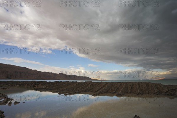 Sunset. Incredible lighting effects on the Dead Sea in Israel. Picturesque sediment mixture of sea salt and mud on the beach
