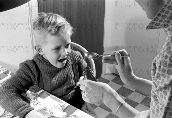 A boy is sick and won't take his medicine. His mother holds out a spoon and waits for him to gape and take it, and he does. He opens his mouth and takes it even though it for sure does not tase so good. Sweden 1956. Conard ref 3157