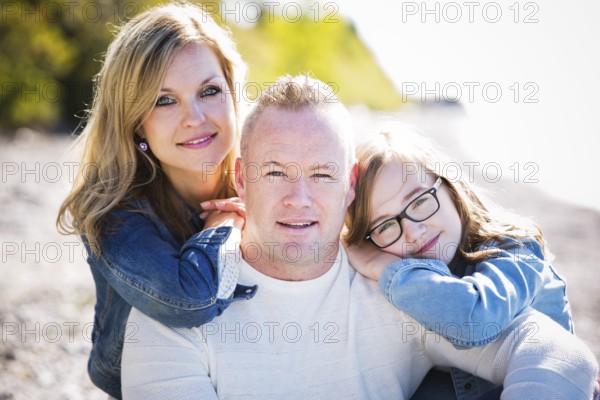 Family of three, mother father and daughter caually posing on the beach, Toronto, Canada, North America