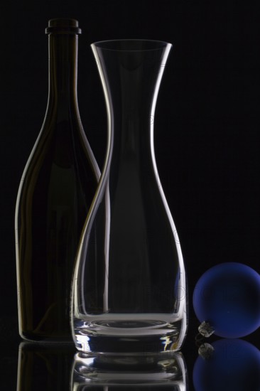 The bottle of wine, glass carafe and Christmas decoration on a black glass desk