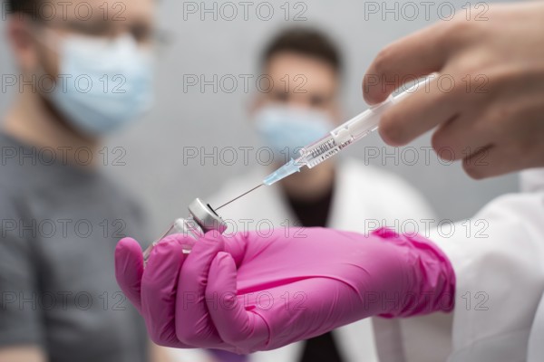 In a practical lesson, a young nurse shows medical trainees how to correctly draw a medicine from a vial using a syringe. An injection with a new vaccine formulation against COVID19 and other infectious diseases in this group