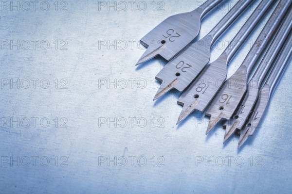 Metal spade bits for drilling wood on metallic background construction concept