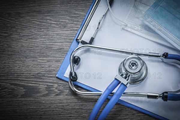 Stethoscope clipboard disposable surgical mask on vintage wooden board