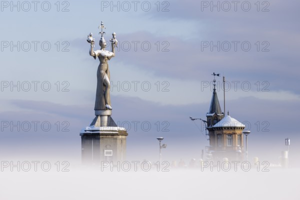 A large statue of Imperia and a small tower rise out of a misty winter landscape, Constance harbour, Lake Constance, Baden-Württemberg, Germany, Europe