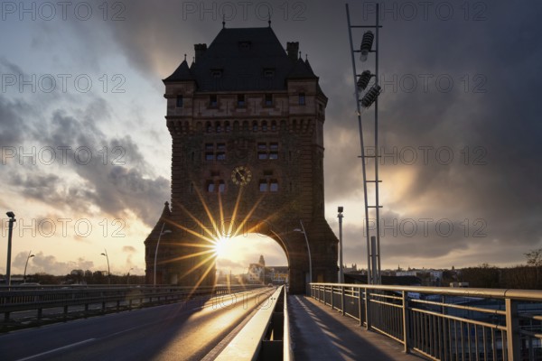 A road or motorway leads through an old historic city gate. Sunset in the evening over the Rhine near Worms, Germany, Europe