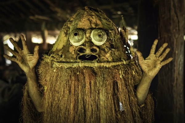 Photo of native man in costume with raised hands in Palembe, Sepik river in Papua New Guinea. In this region, one can only meet people from isolated local tribes