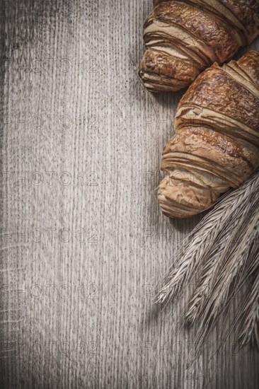 Golden wheat rye ears baked croissants on a wooden board