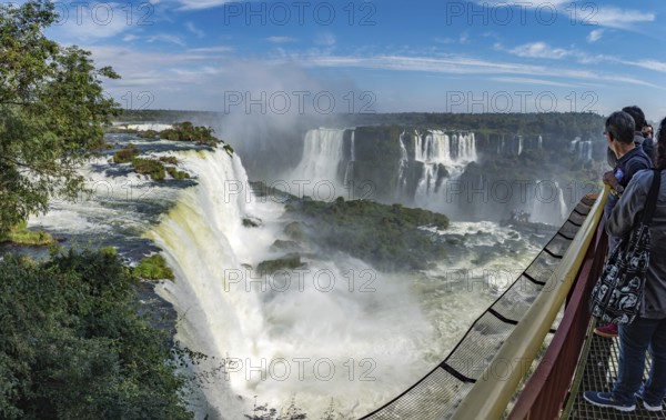 Foz do Iguacu, Brazil, july 9, 2016: Cataratas waterfalls view from the top with some rocks covered by grass in near the waterfall and bright blue sky as background, South America
