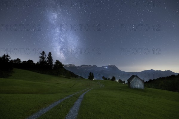 A clear night with a view of the Milky Way over a meadow and a remote hut with a mountain view, Fähnerenspitz, Brülisau, Appenzell Innerrhoden, Switzerland, Europe