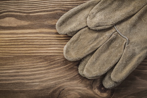 Leather protective gloves on vintage wooden board Construction concept
