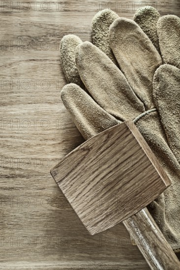 Pair of leather protective gloves Wooden hammer on wooden board '