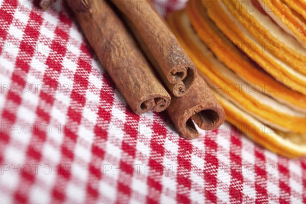 Slices of dried orange and cinnamon sticks on a chequered cloth