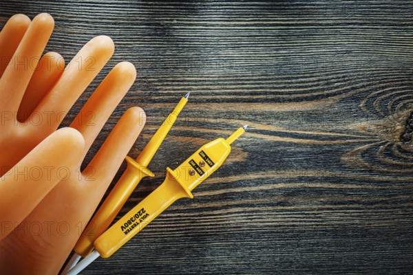 Pair of insulating gloves Electrical tester on wooden board