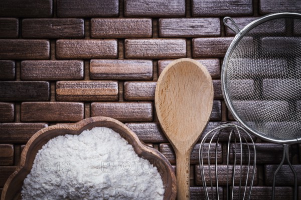 Wood spoon bowl flower sieve and egg-whisk on wooden matting