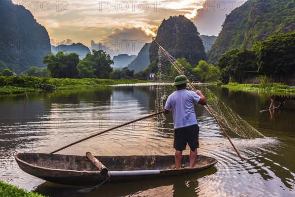 Fisherman on boat in Trang An, a scenic area near Ninh Binh, Vietnam inscribed as a UNESCO World Heritage Site in 2014