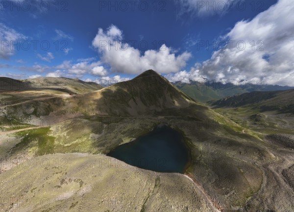 Aerial view of high mountain glacial lake and snow capped mountain peaks. Landscape of an alpine lake on a sunny day