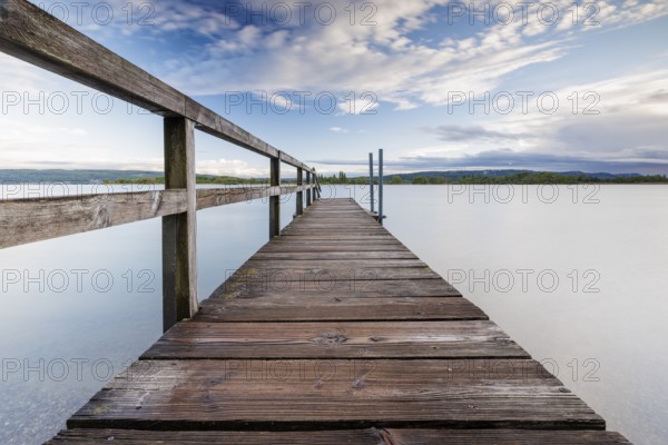 Long wooden footbridge leads into a quiet lake under a partly cloudy sky, Naturfreundehaus, Markelfingen, Untersee, Lake Constance, Kreis Konstanz, Baden-Württemberg, Germany, Europe