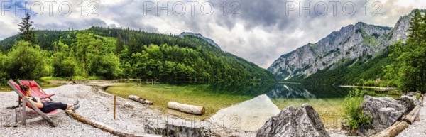 Landscape panorama with woman on sunbed next to the lake Leopoldsteinersee, Styria, Austria. Travel destination in Austria