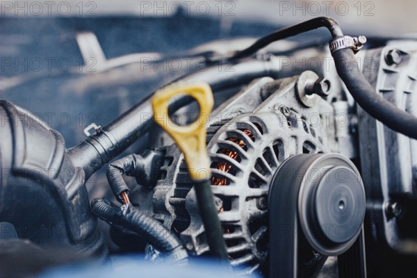 Close view of a car's engine with focus on the alternator and belt, indicating repair work