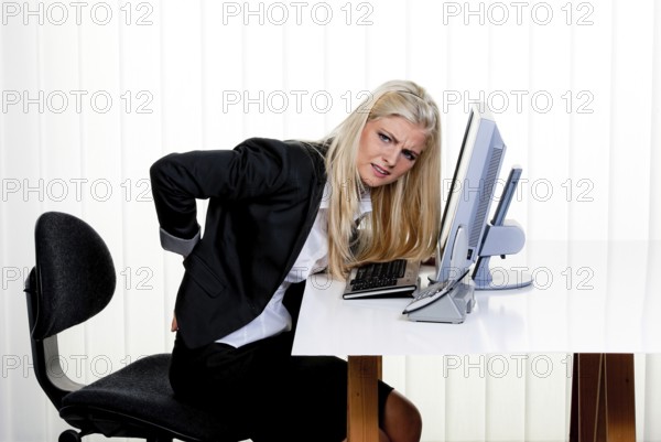 Young woman with back pain in the office