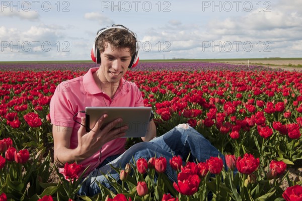 Man in Dutch landscape is listening to the digital tablet PC