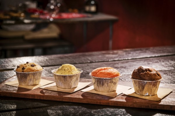 Mixed freshly baked muffins on table in cozy coffeeshop interior