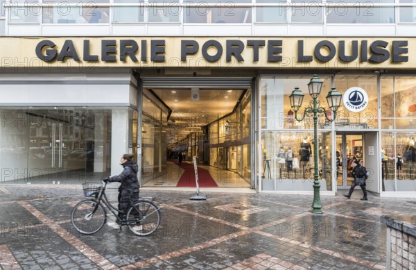 Brussels Old Town, Brussels Capital Region, Belgium, 12 12 2019 Woman with bicycle and pedestrians walking by the Galerie Porte Louise entrance, Europe