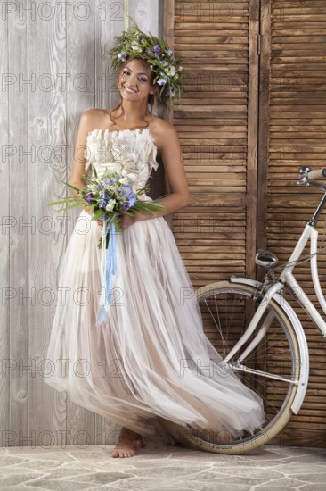 Young beautiful girl in a wedding dress with a bicycle