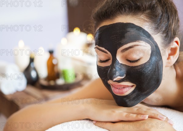 Young beautiful woman in a mask for the face of the therapeutic black mud. Spa treatment