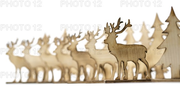 Deer figure sawn out of wood with dark edges and wooden fir trees cut out on white